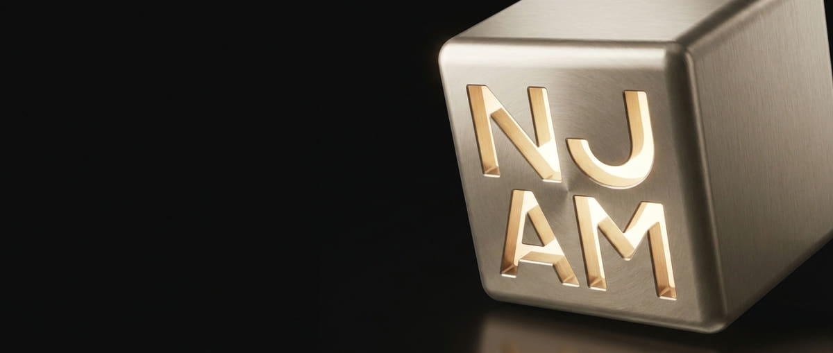 The closed champagne-metal NJAM cube, NJ stacked over AM, resting on black.